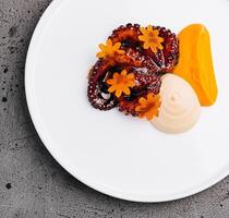 Gourmet octopus salad with carrot flowers on white plate photo