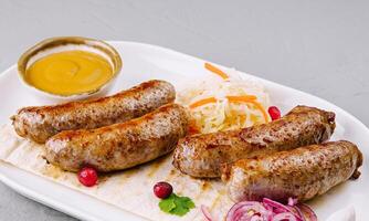 Grilled sausages with sauerkraut and mustard on plate photo