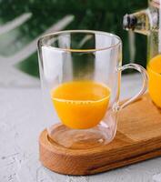 Freshly blended orange smoothie in glass and pitcher photo