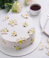 Elegant white floral cake with tea setting photo