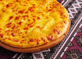 delicioso queso Pizza en tradicional Manteles foto