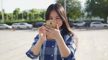 jovem ásia mulher usando inteligente telefone tábua dentro a cidade ruas video