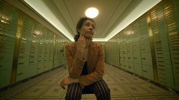 a woman is sitting in a hallway with lockers thinking about future investment video