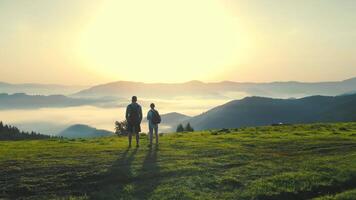 soluppgång på topp av de berg. man och kvinna beundra de skön landskap. morgon- dimma i en berg dal. de skönhet av de ukrainska karpaterna. två turister på en bakgrund av soluppgång video