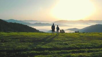 un hombre y un mujer en parte superior de un montaña reunirse el amanecer. Mañana niebla en un montaña valle. hermosa paisaje de el ucranio montes de Cárpatos para dos turistas video