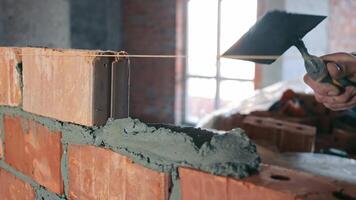 Close-up of Mortar Application on Brick Wall, Close-up of a construction worker's hands applying mortar on a brick wall, demonstrating precision in bricklaying techniques. video