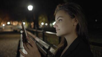 jovem mulher usando tábua computador dentro a parque às noite video