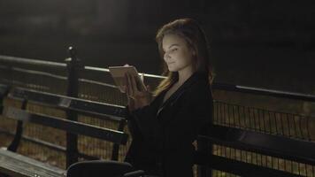 jovem mulher usando tábua computador dentro a parque às noite video