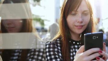 ciudad estilo de vida retrato de atractivo confidente mujer mirando en inteligente teléfono video