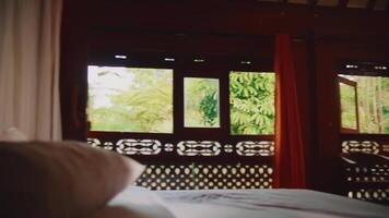 Blurred interior view, cozy bedroom with soft bedding and a glimpse of greenery through the window, conveying a peaceful atmosphere. video