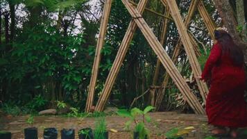 Two people in traditional attire dancing in a garden with wooden structures and greenery video