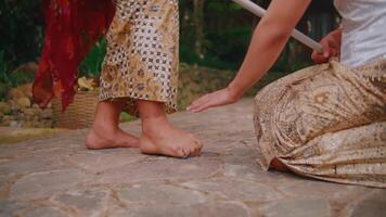 fechar-se do dois pessoas dentro tradicional vestuário em pé em uma pedra caminho, com uma foco em seus nu pés e estampado roupas. video