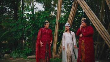 Tres mujer en tradicional atuendo teniendo un conversacion en un jardín con bambú estructuras video