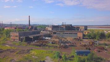 View of the work area from the drone. Clip. A large factory with pipes from which smoke is coming, the city and the forest and the calm sky are visible from behind. video