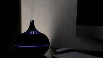 Aromatherapy oil diffuser with colorful LED light from which steam comes out on a dark background. Concept. Aromatic humidifier on a table at home. video