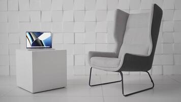 portable sur une cubique en forme de café table dans une moderne bureau. action. minimaliste conception de le pièce avec une confortable chaise et une ordinateur sur une petit tableau. video