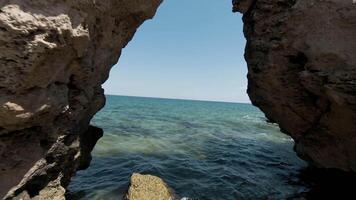 Aerial view of rocks and sandy sea shore, summer and holiday concept. Action. Flying through the stone arch with the endless ocean behind the horizon. video