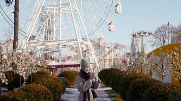 voorjaar amusement park . actie. een reusachtig recreatie park waar een veel van mensen wandelen en een reusachtig wit ferris wiel in de achtergrond. video