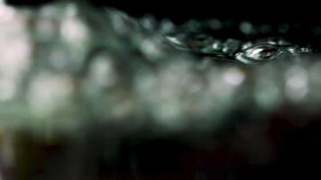 Close up of boiling wayer with moving air bubbles on a black background. Stock footage. Concept of cooking or making hot beverage. video