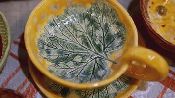 Yellow ceramic cup and saucer with leaf inside. ART. Beautiful handmade tea pair. Grape leaf imprint inside the mug video