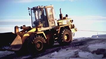 GERMANY, BERLIN - MARCH 17, 2022. Big tractor at the north pole. CLIP. In the foreground, a tractor is pulling a heavy load. In the , people walk and tractors work on an icy space video