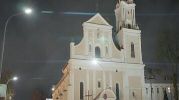 gammal katolik kyrka i natt stad. handling. skön ljus tempel upplyst på natt. katolik kyrka med torn i modern stad video