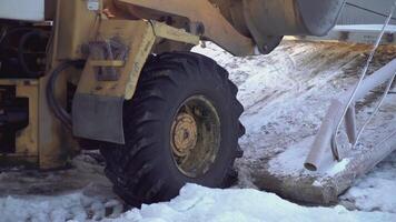 das Bulldozer zieht etwas aus mit ein Eimer. Clip. Nahansicht auf das Räder und Eimer von ein Gelb Rolltreppe. im das Schnee, ein Bulldozer dreht sich es ist Räder wann es zieht etwas schwer video