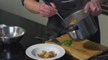 The cook puts the cooked dumplings out of the pan into a white plate.ART. A person adds a ready-made dish to the plate with a colander video