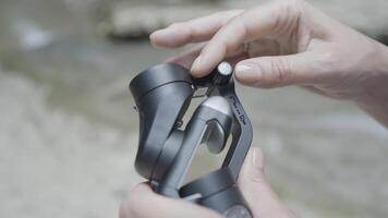 Shooting a waterfall using a camera device. Action. Beautiful nature with mountains on which a young beautiful girl shoots water drops falling from the mountains on camera. video