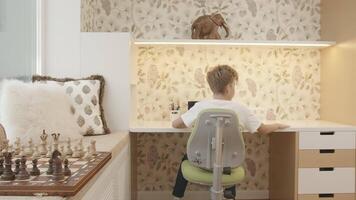 interieur van kinderen kamer met jongen zittend Bij tafel. creatief. jongen is aan het studeren Bij bureau. kinderen kamer van slim jongen aan het studeren Bij tafel video