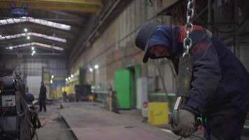 MOSCOW, RUSSIA - FEBRUARY 25, 2022 . A man at a factory hooks equipment. CLIP. Machine drive on a metal hook in an industrial building. A guy in work clothes works at a factory video