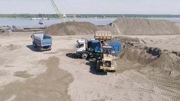 The excavator loads the dump truck with sand and soil. Scene. Aerial view of the equipment prepares the construction site for the construction of an apartment building. video