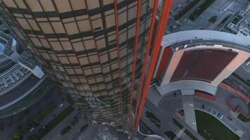 Top view of round glass high-rise. Stock footage. Rounded architecture of tall business building. View from glass skyscraper down to square in summer video