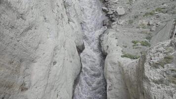 un' potente ruscello di acqua è spremuto fra il lati di il rocce. azione. aereo Visualizza di il fiume fluente nel un' gola fra montagne. video