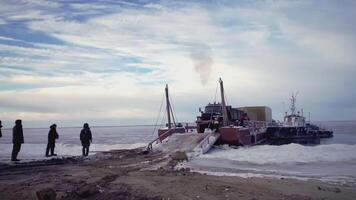 AUSTRIA, VIENNA- MARCH 17, 2022. People stand in the cold and watch the shipment of the liver. CLIP. They brought a large car and ship it to the shore. At the end, caterpillar vehicles come to the video