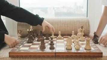 proche en haut de mains en jouant échecs. créatif. une main de une enfant qui fait du une bouge toi dans une échecs jeu, en bois pièces sur une échiquier. video