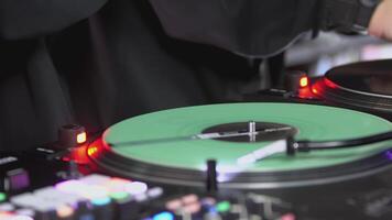 DJ spinning record at disco. Art. Close-up of DJ's hand on mixer. Glowing music panel at party. Musician's work in nightclub video