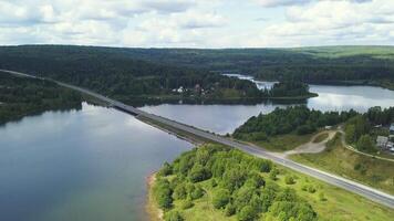A huge bridge across the river. Clip. Bird's-eye view. A huge bridge over a large river against the background of a cloudless sky and huge forest trees. video