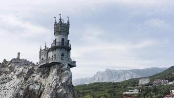 aereo Visualizza di sorprendente di rondine nido a gaspra nel Crimea, Russia. azione. fiaba castello costruito su il scogliera superiore con verde valle e blu cielo su il sfondo. video