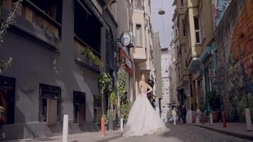 bellissimo donna nel nozze vestito su vecchio europeo strada. azione. bellissimo nozze foto di sposa nel vestito su sfondo di vecchio città strada video