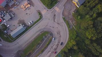 View from a helicopter . Clip. View of a curving road with cars next to a green park and some kind of base with parking video