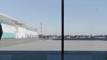 un silueta de un empresario utilizando teléfono inteligente, teniendo teléfono llamada y caminando en frente de panorámico ventanas hdr. grave hombre con un teléfono inteligente adentro por el ventana en azul cielo antecedentes. video