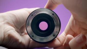 Close-up of man rotating lens. Action. Photographer turns ring of professional lens on isolated background. Lens of lens changes size from rotation of ring by photographer video