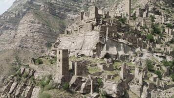 Aerial view of an ancient abandoned stone village with ruined buildings. Action. Rock cliff with old towers and constructions on a sunny day, concept of archeology. video