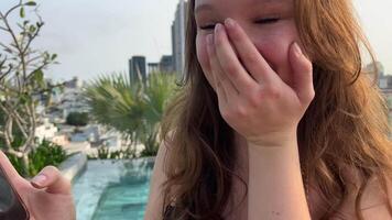 A young woman shows her phone, talks about the news, joy, laughter. very satisfied happy girl near the pool received good news on the phone, laughs, rejoices, smile of happiness video