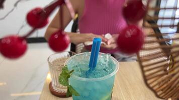 a piece of mint and lime being placed into a blue mint julep cocktail surrounded by pinecone moss and glowing blue ice cubes then a straw being placed inside of it STATIC PULLOUT DOLLY BACK video