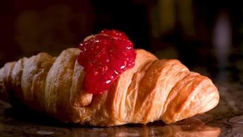 framboos jam is gegoten Aan een croissant een veel van jam stromen naar beneden Aan vers gebakjes poreus structuur een steen tafel toetje van snoepgoed een veel van zoet is schadelijk naar Gezondheid ontbijt voor koffie video