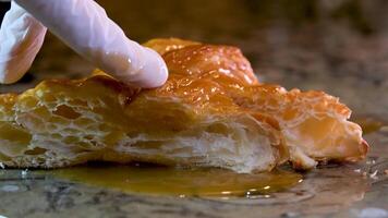 appetitoso poroso struttura di un' brioche mano prende lontano completamente fluente caramello sciroppo delizioso dolcezza mangiare con mani servire per il tavolo degustazione qualità dai un'occhiata culinario concorrenza video