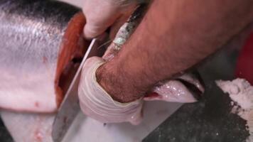 jefe manos cortar salmón filete con cuchillo en de madera mesa a cocina. mujer Cocinando rojo omega pescado con limones para sano nutrición dieta video