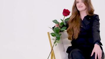 gettare un' rosa su un' cranio testa Rossa adolescenziale ragazza si siede a il finestra con rosa nel malinconia umore giovane donna con un' mazzo di rosso Rose vicino un Aperto finestra. un' bellissimo ragazza gode il aroma di fiori video